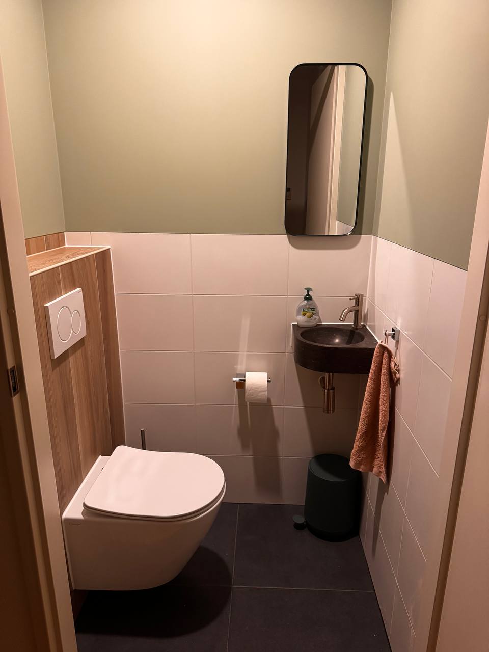 Onze renovatie van een compacte toiletruimte met groene wanden, houtlook en zwarte wastafel